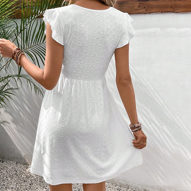 Person wearing a white dress with a textured pattern, standing against a neutral background.