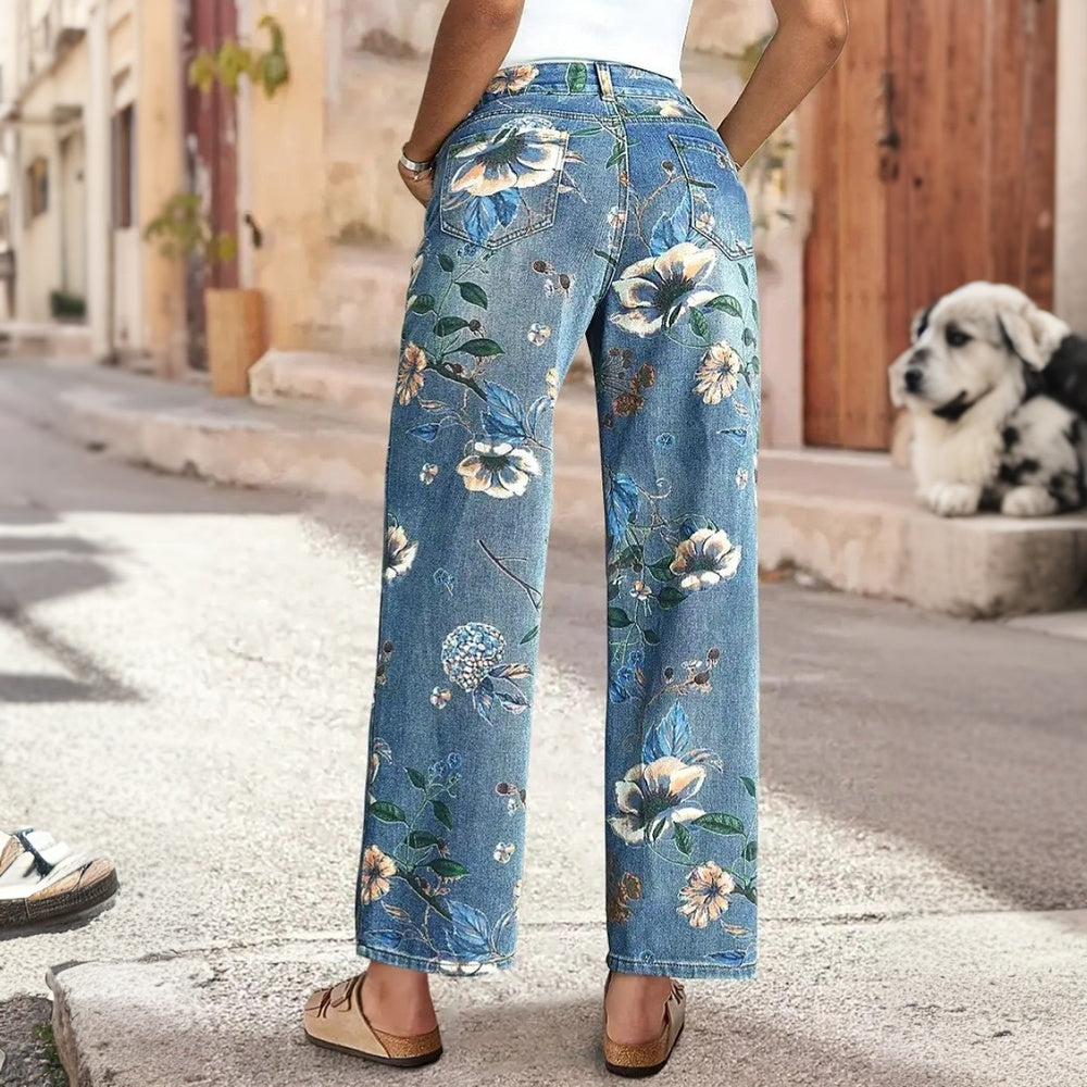 Person wearing floral blue jeans standing on a street with a dog in the background