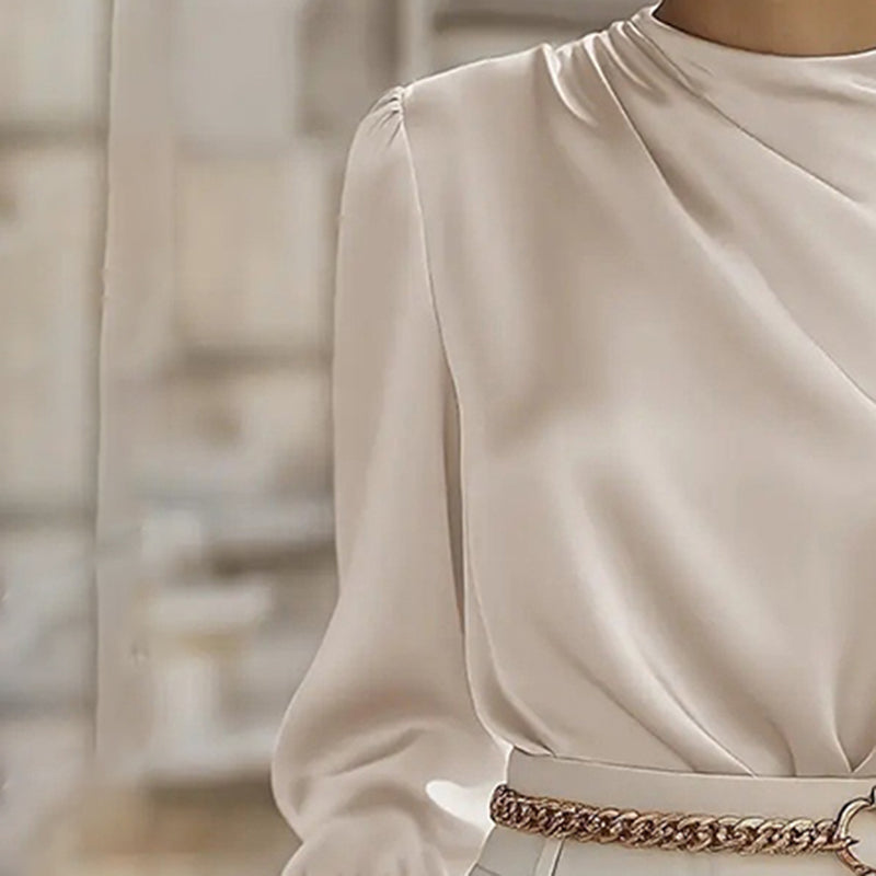 Close-up of a person wearing a beige long-sleeve top with a blurred background