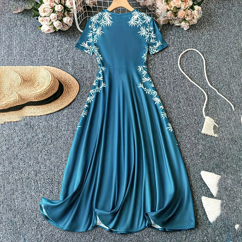 Blue dress with white floral embroidery on a gray surface with a hat and flowers.