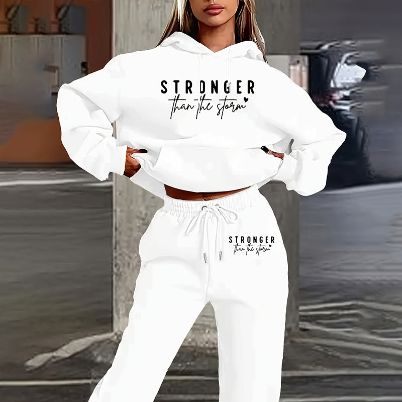 Person wearing a white hoodie and pants with 'Stronger Than The Storm' text, standing on a street.