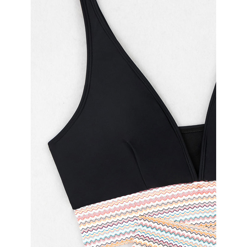 Black bikini top with a colorful striped bottom on a white background