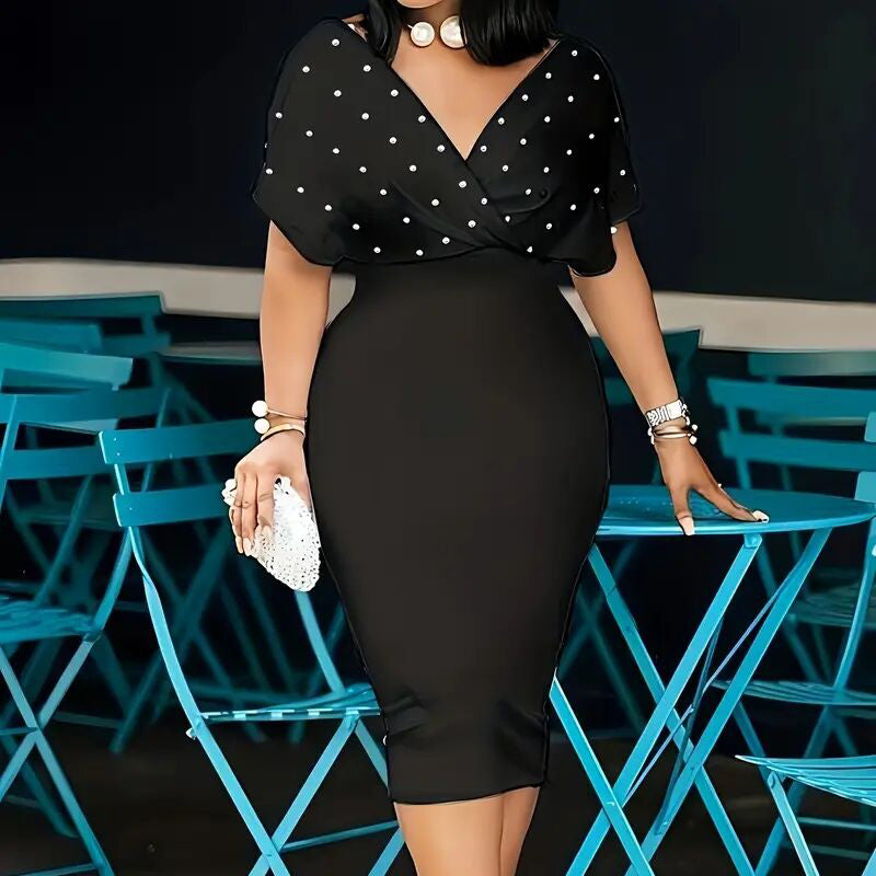 Woman in a black dress with white polka dots standing in front of blue chairs.