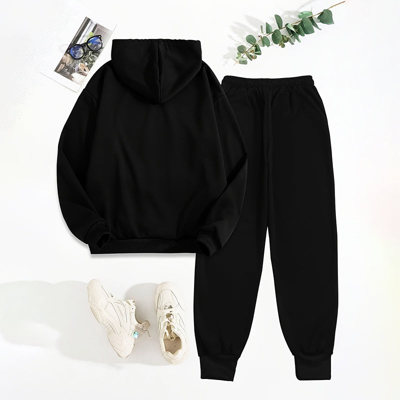 Black hoodie and jogger pants set with white sneakers on a light background