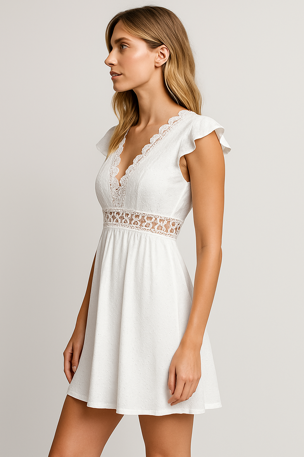 Woman wearing a white dress with lace details on a plain background