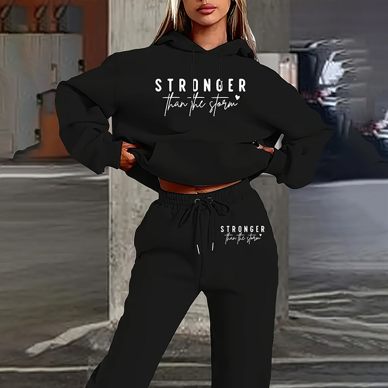 Person wearing a black hoodie and pants with 'Stronger than the storm' text in an urban setting.