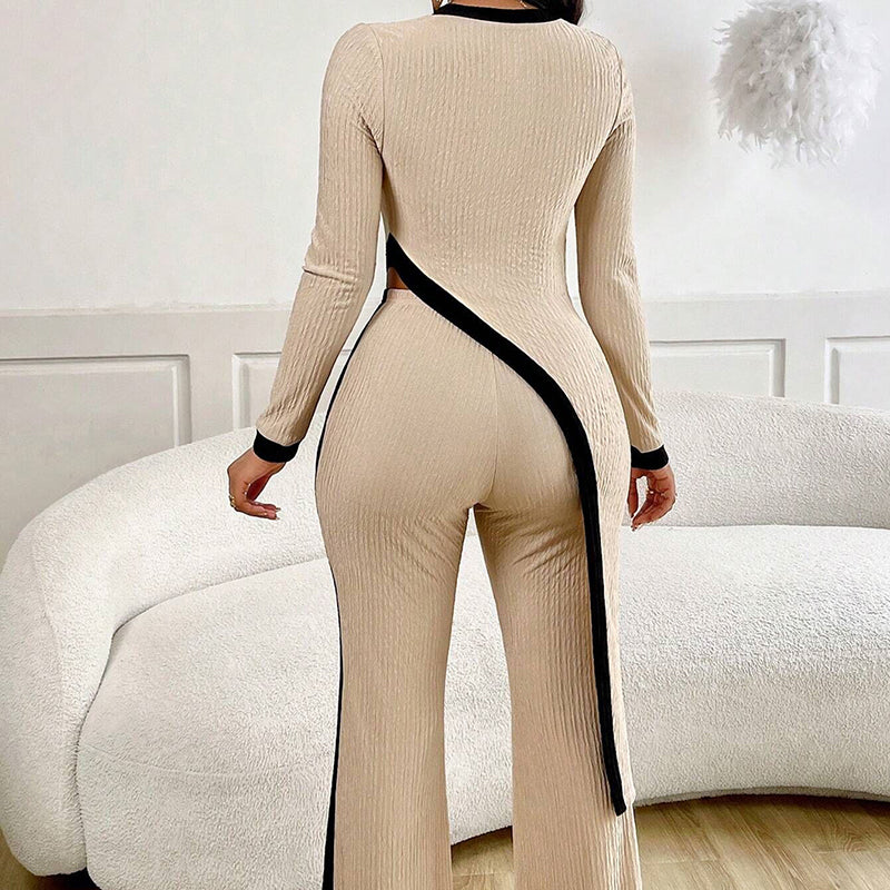 Person wearing a beige ribbed jumpsuit with black trim in a room.