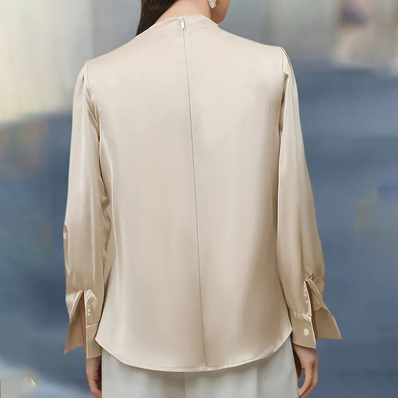 Beige blouse worn by a person with a blurred background