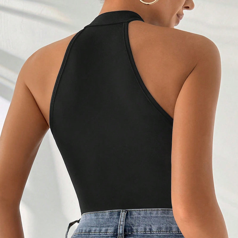 Person wearing a black halter top and blue jeans on a neutral background